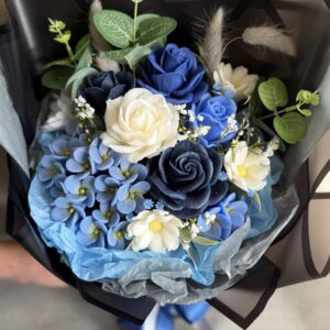 Handmade blue soap flower bouquet with navy, dusty blue and ivory roses, blue hydrangea, white daisies and decorative greenery.