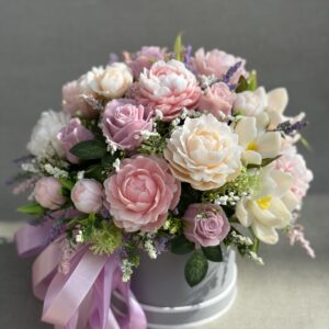Large pastel soap flower bouquet with pink peonies, lilac roses and cream magnolias in a grey hat box with a lilac bow.